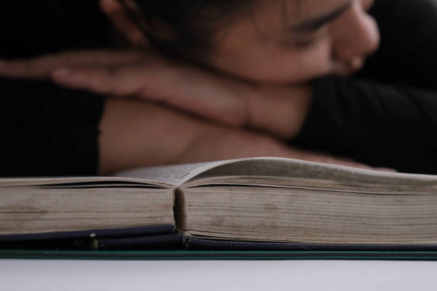 istock Tired young woman lying on a book after hard work. 1480891228