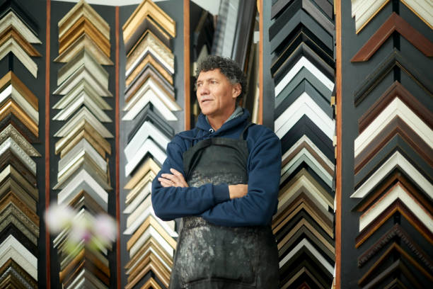 istock Painting, frame and creative with a man designer working in his studio for art or modern decor. Selection, design and retail with a male artist at work as a painter alone in his artistic workshop 1480893908
