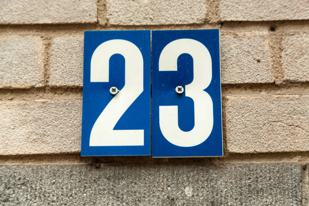 istock 23 plastic numerals on blue plastic plaque on white brick house facade. 1480895606