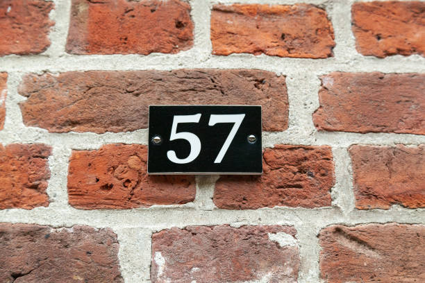 istock 57 number on black plastic plaque on red brick facade. 1480895613