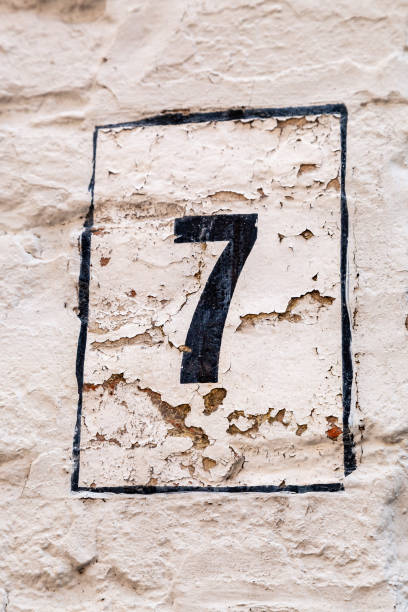 istock 7 number decorative font in black paint handpainted on peeling white painted cement rendered house wall. 1480895640