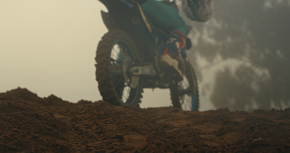 Motorcycle, sports and back view of dirt biker on sand, soil or dust road training for competition. Motorbike, stunt driver and rider practicing for event on off road terrain or track outdoors alone.