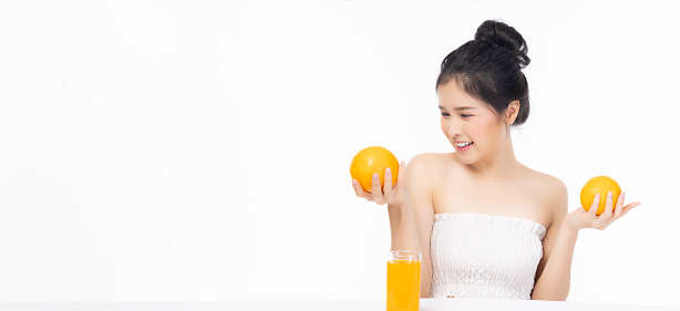 Diet girl Beautiful young lady hold fruit or orange look at orange fruit Pretty woman has good health and healthy skin She love drinking orange juice and eating fruit Health Care and Beauty concept