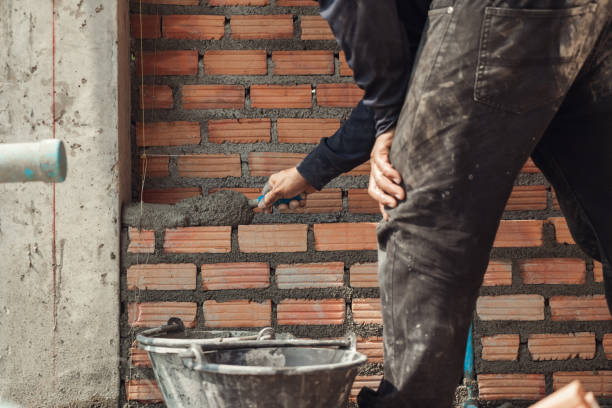 istock Bricklayer with trowel to installing red bricks masonry and  PVC pipe in a new wall. 1480897414