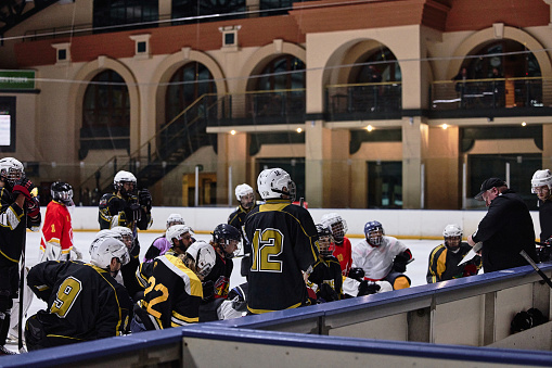 Hockey, team training and coaching strategy, coach and talking about game plan, ice rink or group listening to advice. Sports men, discussion or teamwork in practice, sport or fitness with ice hockey