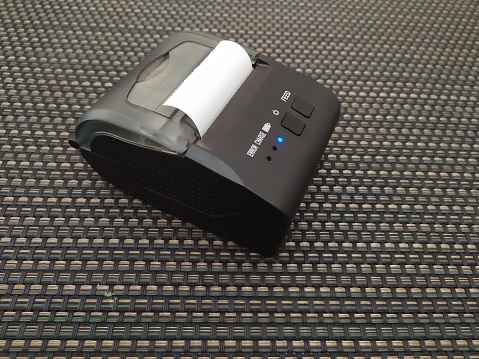 portable bluetooth printer on a dark background, which is usually used for printing receipts