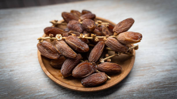 istock Dry branched dates on a wooden plate 1480902766