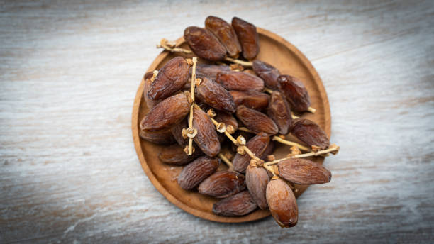istock Dry branched dates on a wooden plate 1480902810