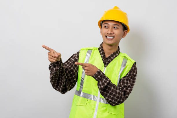 istock Smiling young asian construction pointing with his fingers to the side copy space isolated on white background. Marketing and advertising concept. 1480903478