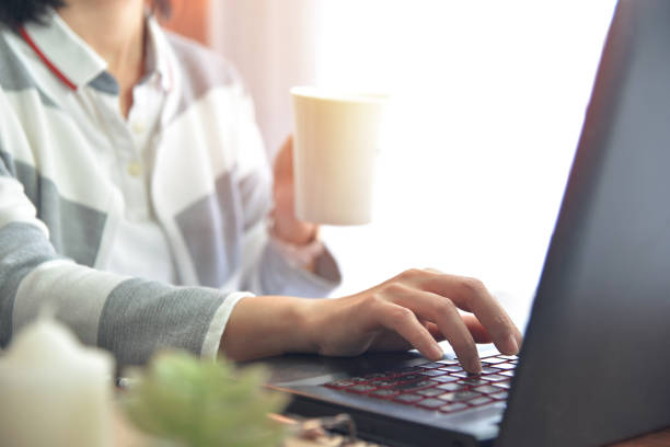 istock Hands of a woman holding a cup of coffee while using the keyboard 1480903601