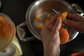 Female hands cut fresh delicious ripe peaches into a plate