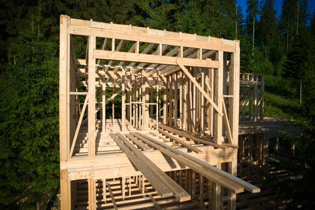 Wooden frame house under construction near forest.