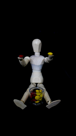 Wooden doll with red and yellow candies, dimly lit