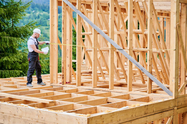 istock Carpenter measures distance with tape measure while building wooden frame house. 1480913984