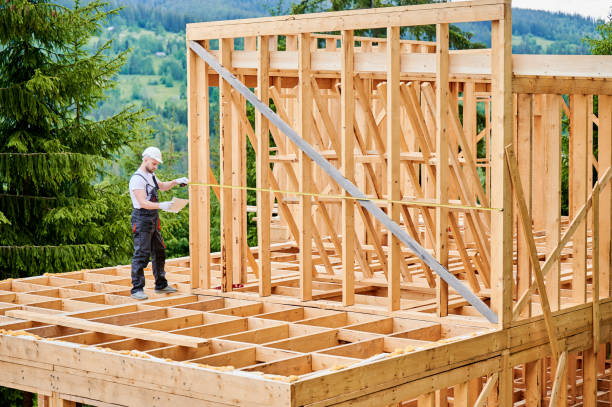 istock Carpenter measures distance with tape measure while building wooden frame house. 1480913990