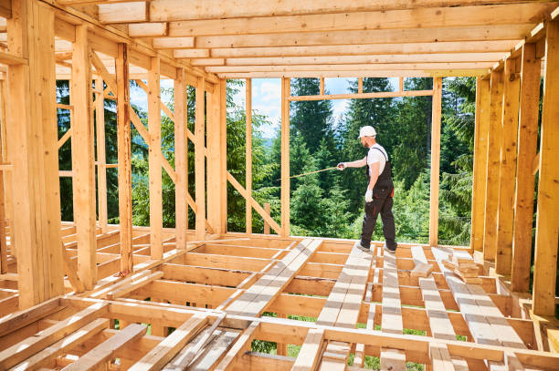 istock Carpenter measures distance with tape measure while building wooden frame house. 1480914017