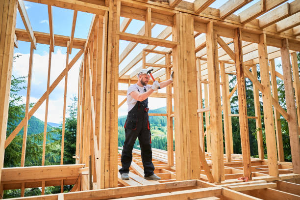 istock Carpenter hammering nail while constructing wooden frame two-story house near the forest. 1480914024