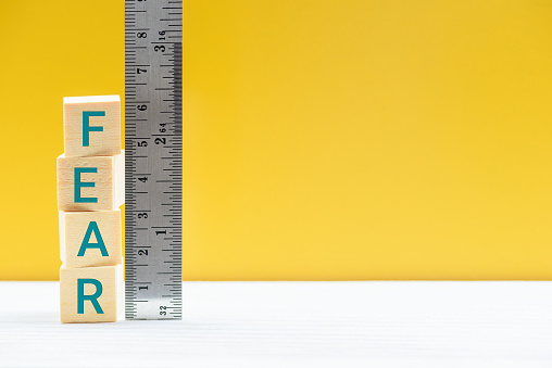 Evaluation, measurement of fear, emotion recognition concept : A ruler with numeric scale measures square cubes with the word FEAR, depicting value of fear that derive from things we are afraid of.