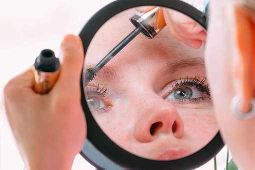 Woman Applying Mascara in Magnifying Makeup Mirror