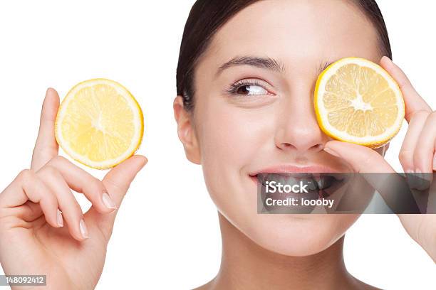 A Woman Holding A Slice Of Lemon Over Her Eye Stock Photo - Download Image Now - Fruit, Beauty Product, Human Face