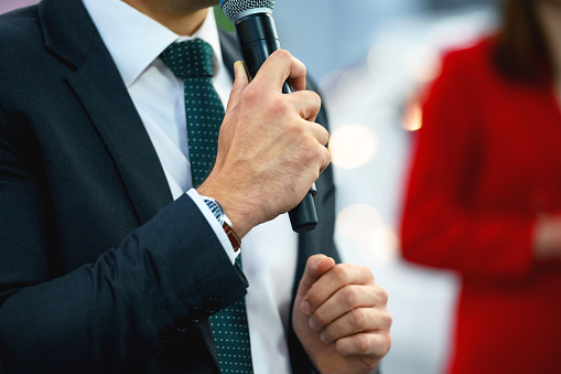 Public figure holds a microphone and addresses the audience at a public event