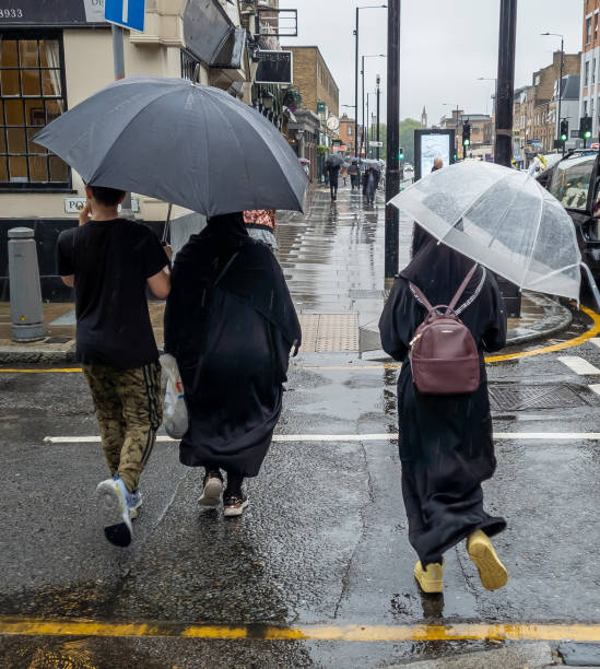 piétons dans la rue pendant les fortes pluies après une sécheresse record et une vague de chaleur estivale. - pedestrian accident england street photos et images de collection