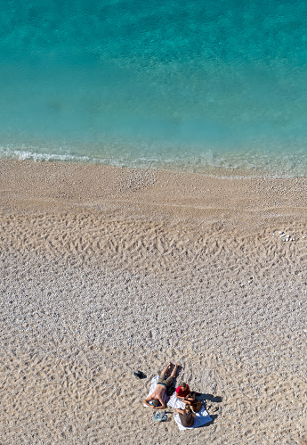 Lefkada island. Greece-10.21.2022. A couple relexing on Porto Katsiki Beach on holiday enjoying the sunshine and crystal clear sea.