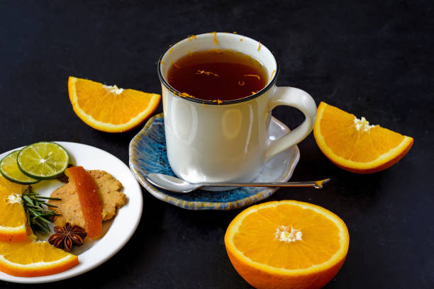 istock Orange cinnamon tea with crystalized fruits and cookies on black bacground 1480926680
