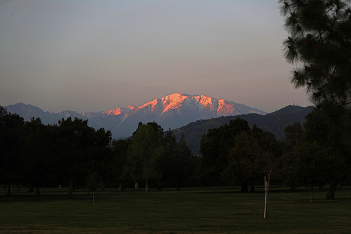 As darkness cloaks the San Gabriel Valley floor the last fiery rays of sunset give golden hues upon the snow capped slopes of Mt Baldy.