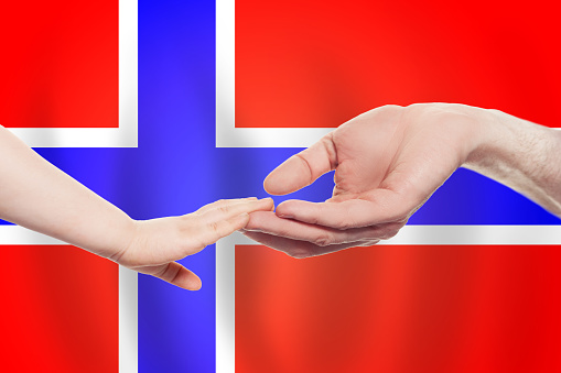 Norwegian baby and parent hands on the background of flag of Norway Help, aid, support, charity concept