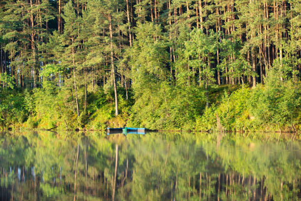 Boats at rest on a placid lake. Many rowboats are resting on this placid lake, lying on the jetty. In the background stands the building of the Spremberg Dam and a power station. The Spremberg Dam lie between Cottbus and Spremberg, in the south east of Brandenburg. The lake impounds the River Spree. The Spremberg Dam itself is made of earth and is the only one in Brandenburg that counts as a large dam.