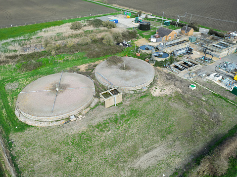 Aerial drone view of a rural sewage treatment plant seen between arable agricultural fields in East Anglia, UK.