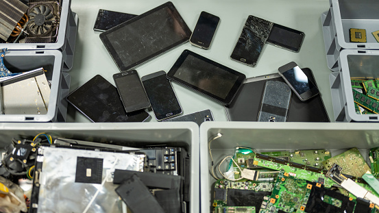 Broken digital tablets, smartphones and electronic waste on table repair service workshop top view