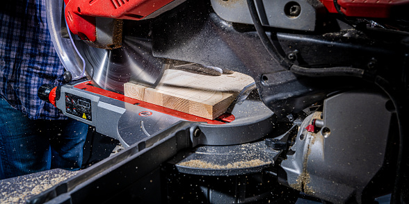 Circular saw cutting wooden plank in carpentry workshop close up