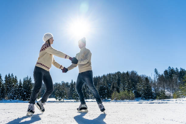 istock Couple holding hands while ice skating on lake 1480934353