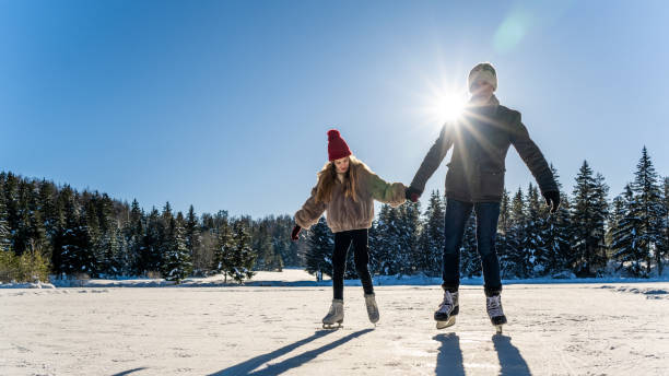 istock Daughter ice skating with father on frozen lake 1480934367
