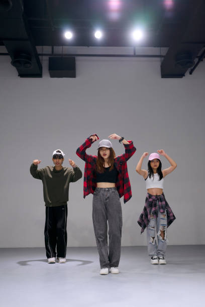 Dancing mixed race young girl in colourful studio light. Stylish female dancer performer show hip hop dance. Copy space. High quality photo