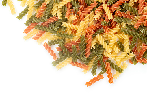 Raw colored pasta fusilli on white background. Space for text. Top view.