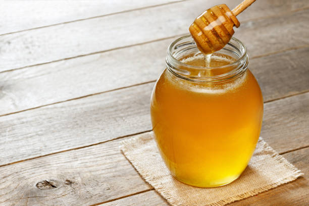 istock honey pouring from dipper in jar on wooden table 1480942698