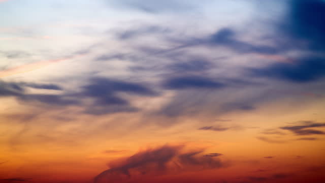 Sunset sky with red light of the setting sun, timelapse. Evening clouds in the orange light of sunset rays, time lapse