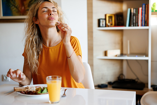 Smiling young woman enjoying breakfast at home