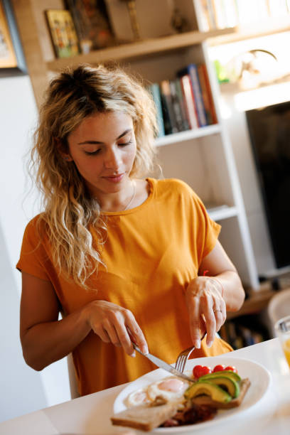istock Smiling young woman enjoying breakfast at home 1480950460