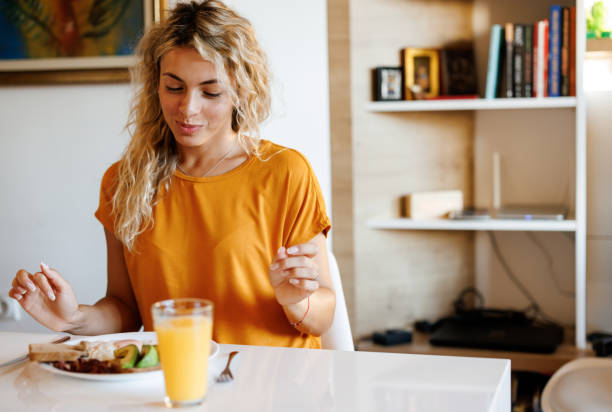 istock Smiling young woman enjoying breakfast at home 1480951444