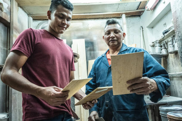 istock Father and son talking while analyzing pieces of wood at carpentry 1480951582