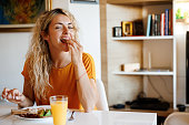 Smiling young woman enjoying breakfast at home