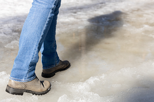 man walking on ice in the park. a woman walks through a puddle in winter. man walking in the snow. man steps into a puddle.
