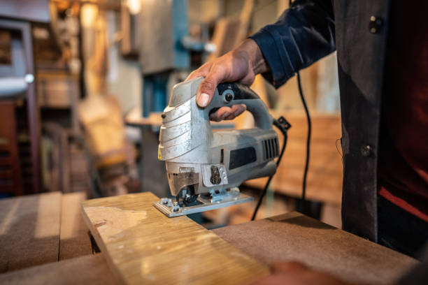 Close-up of a nan using an electric jigsaw at carpentry workshop
