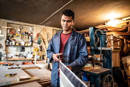 Young man cutting cloth fabric in carpentry workshop