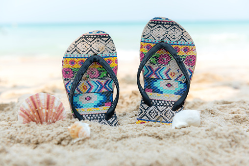 Summer Fashion tourism woman accessories to travel in the beach.  Sandals traveler on the sand beach.  Summer and Trips Concept