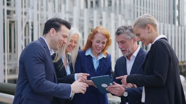Surprised business people looking the screen of a tablet outdoors